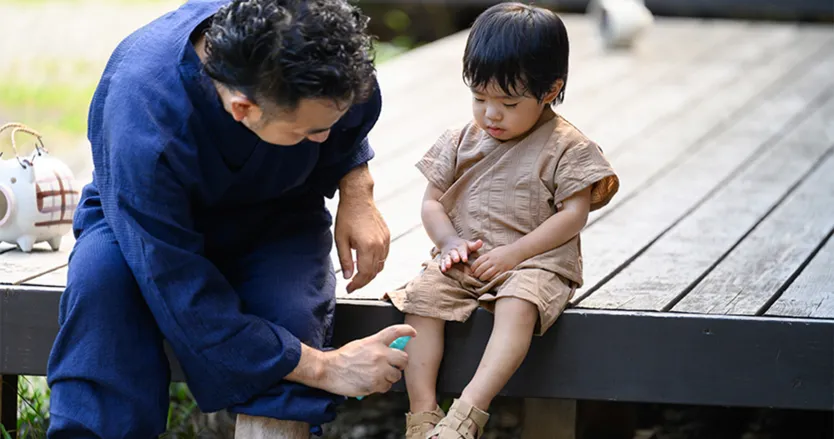 Father spraying insect repellent on young child