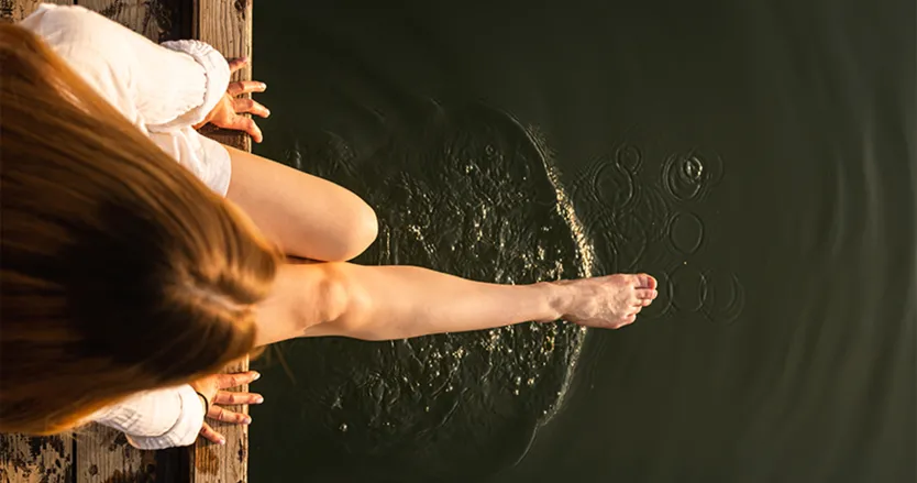 Woman sitting on dock with her feet in the water