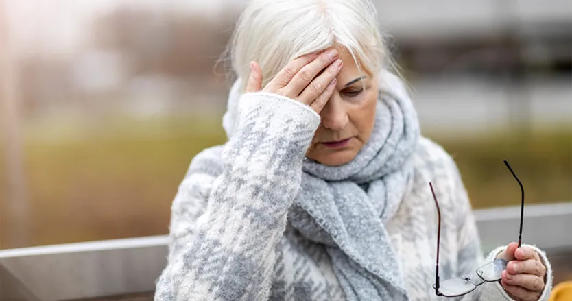 Older woman with her hand to her head as if she's in pain