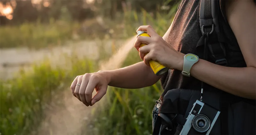 Women spraying insect repellent on her arm