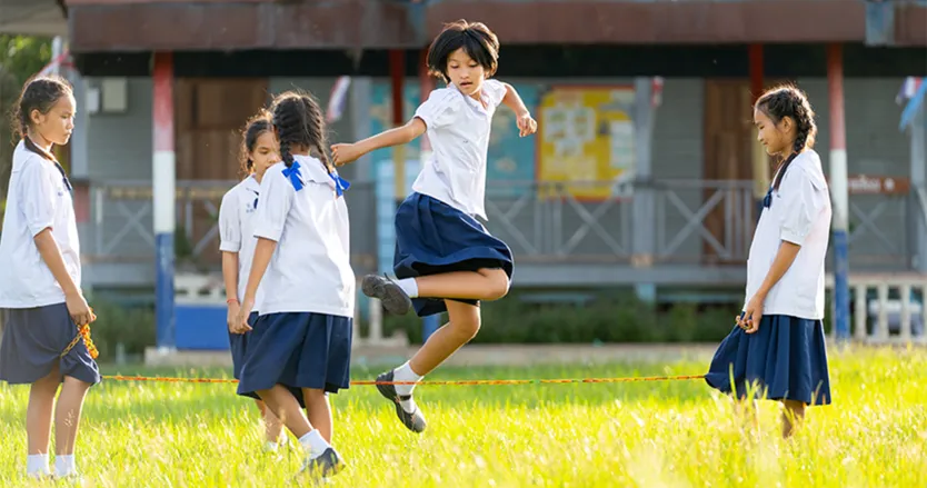 Group of girls in school uniforms in the school yard playing jump rope