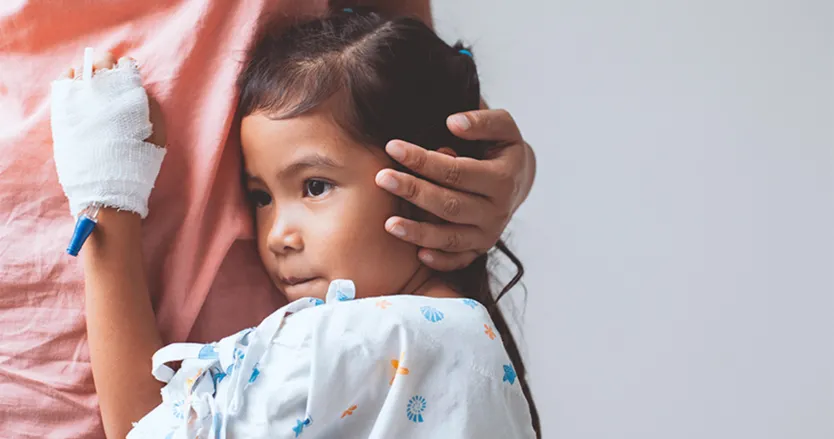 Little girl with IV port in her hand hugging an older female