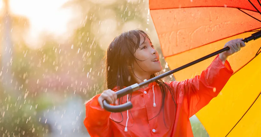 Young girl in the rain with an umbrella and a rain coat on