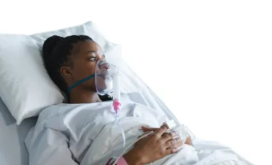 Young woman lying in hospital bed with a breathing tube