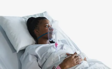 Young woman lying in hospital bed with a breathing tube