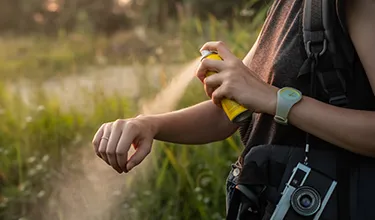 Women spraying insect repellent on her arm